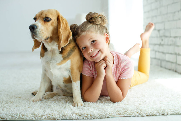 Gyerek kutyával. A kislány egy kutyával játszik otthon. Gyermek és állat. - Fotó, kép