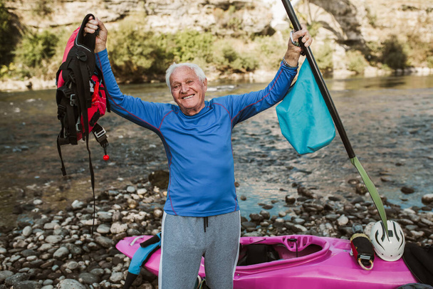Hombre mayor preparándose para la excursión en kayak en un río de montaña. - Foto, Imagen