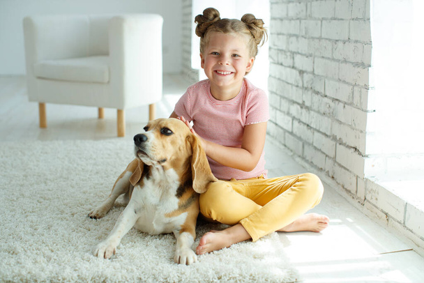 Köpekli bir çocuk. Küçük kız evde bir köpekle oynuyor. Çocuk ve hayvan. - Fotoğraf, Görsel