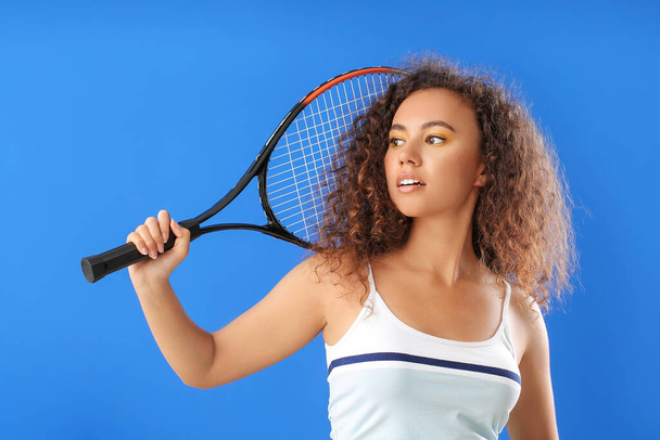 Young African-American woman with beautiful eyeshadows and tennis racket on color background - Photo, Image