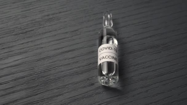 Nuevo primer plano experimental de la vacuna contra el coronavirus. Ampolla con vacuna COVID-19 sobre fondo gris texturizado de madera - Imágenes, Vídeo
