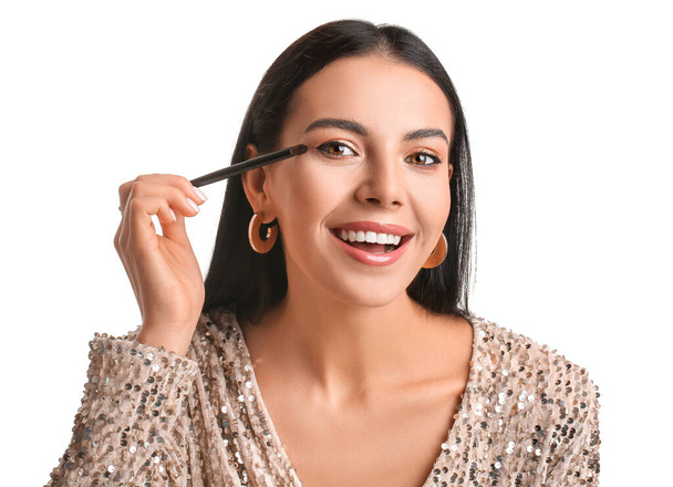 Beautiful young woman applying eyeshadows on white background - Φωτογραφία, εικόνα