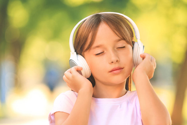 Little girl listening to music in park - Zdjęcie, obraz