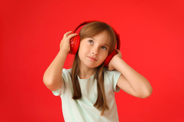 Little girl listening to music on color background - Фото, зображення