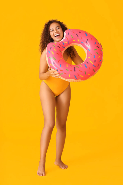 Mooie jonge Afro-Amerikaanse vrouw met opblaasbare ring op kleur achtergrond - Foto, afbeelding