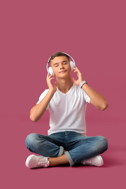 Teenage boy listening to music on color background - Photo, Image