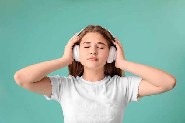 tiener meisje luisteren naar muziek op kleur achtergrond - Foto, afbeelding