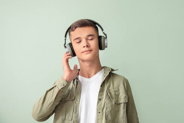 Teenage boy listening to music on color background - Фото, изображение