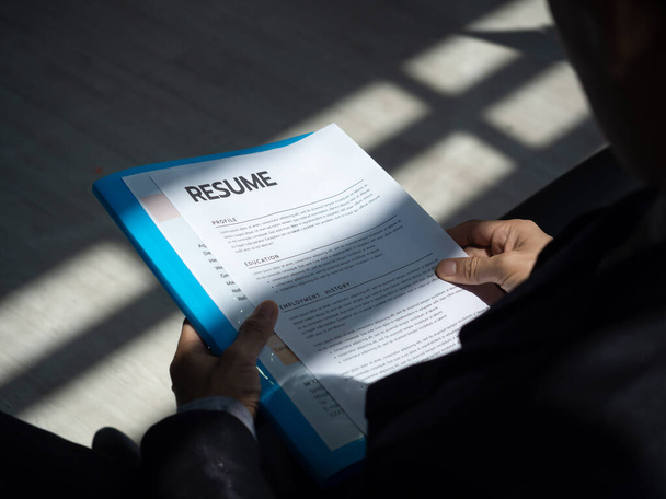 Obnovit dokumenty nebo životopis papíru v rukou nezaměstnaného muže uchazeče v obleku sedí čeká na přijímací pohovory, zaměstnání, nábor a koncepce pracovní žádosti. - Fotografie, Obrázek