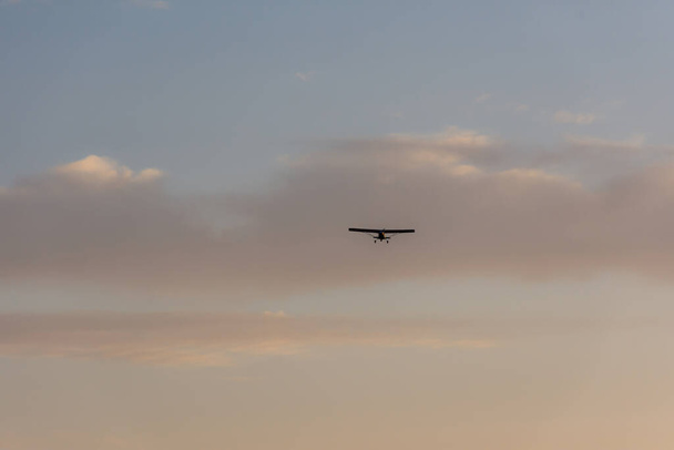 コーナシャー機は空高くあります。フライ小さな飛行機の周り。雲と飛行機で夕日の空. - 写真・画像