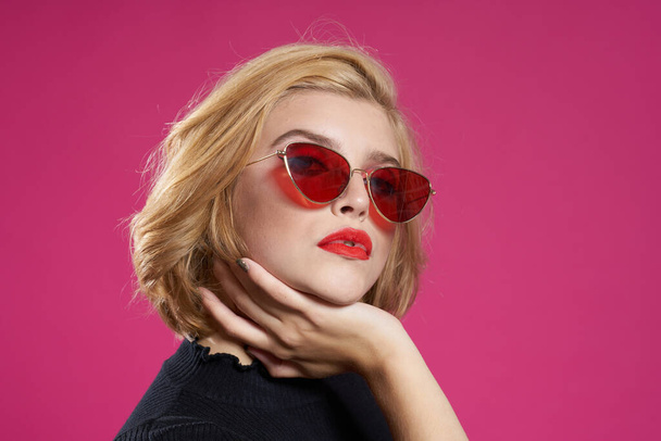 Pretty woman in dark glasses bright makeup black jacket close-up pink background - Photo, Image