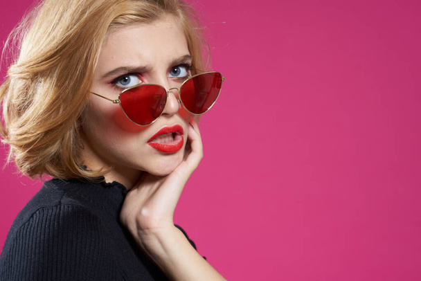 Pretty woman in dark glasses bright makeup black jacket close-up pink background - Foto, afbeelding
