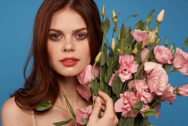 Beautiful woman with a bouquet of pink flowers on a blue background spring model  - Foto, immagini