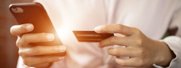 Close-up van een tiener vrouw met een creditcard en smartphone te maken online betaling. Voorraadfoto. - Foto, afbeelding