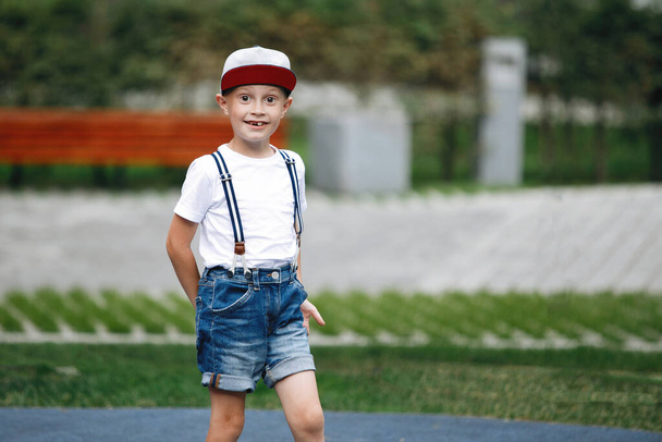 Un niño pequeño en una calle de la ciudad posando ante la cámara. Feliz infancia, al aire libre, amor y cuidado. - Foto, imagen