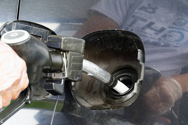 Człowiek tankujący czarny samochód olejem napędowym na stacji benzynowej. Dysza tankująca z bliska i strumień paliwa. - Zdjęcie, obraz