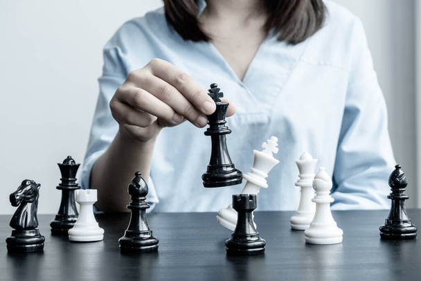The hands of businesswomen moving chess in chess competitions demonstrate leadership, followers, and strategic plans, business success building processes, and teamwork. - Foto, afbeelding