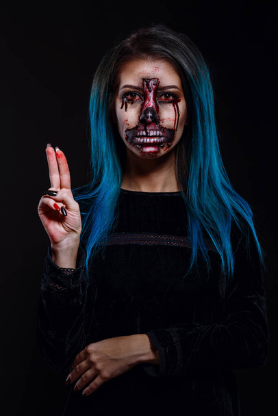 Porträt von blutigen schrecklich gruselige Zombie-Frau in einem Halloween festlichen Make-up. Das Make-up wird in Form einer Gelenkhaut in Form eines umgedrehten Kreuzes hergestellt. Halloween-Plakat. - Foto, Bild
