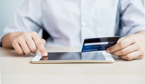 Podnikatelská ruka drží kreditní kartu a pomocí notebooku pro on-line nákupy a internetové platby v kanceláři. - Fotografie, Obrázek