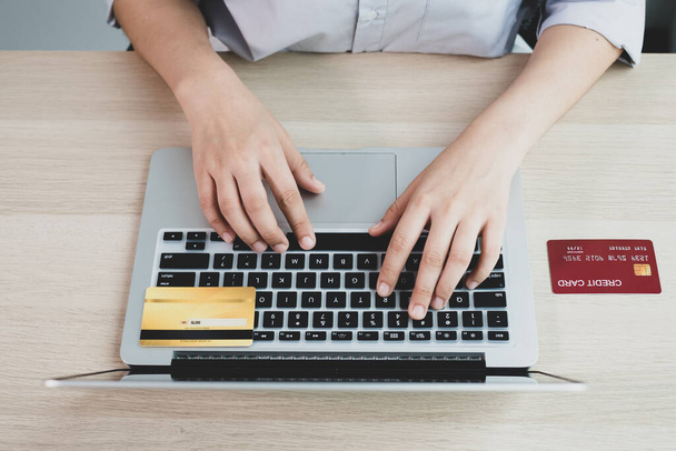 La mano de la empresaria sostiene una tarjeta de crédito y utiliza una computadora portátil para compras en línea y pago por Internet en la oficina. - Foto, Imagen