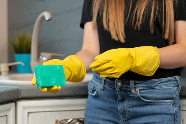 Hands of a woman in yellow gloves holding green sponge - Foto, Imagem