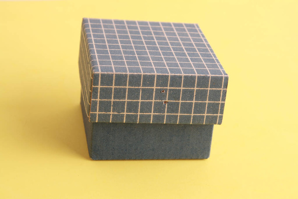 A closeup shot of a small blue cardboard box on a yellow background - Fotografie, Obrázek