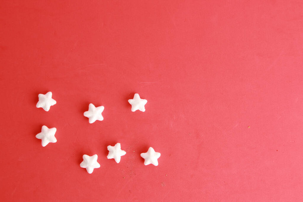 A top view of small white decorative stars on a red background - Photo, Image