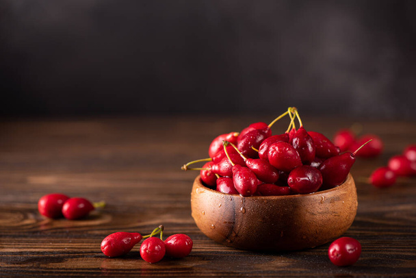 ripe dogwood berries in a wooden bowl - Фото, изображение
