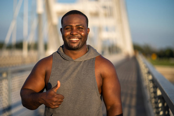 Портрет молодого веселого афро-американца в спортивной одежде, смотрящего в камеру и улыбающегося. - Фото, изображение