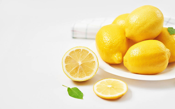 Citrónové pozadí. Skupina citronů s listy na bílém pozadí. Citrusy a vitamíny. Tvůrčí vzhled z citronu a listí. Ležel. Koncept jídla. Vegetariánství a veganství. Léto. - Fotografie, Obrázek
