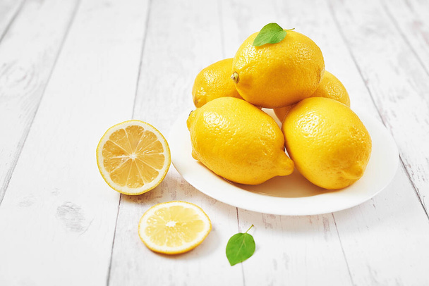 Lemons background. Group of lemons with leaves on white background. Citruses and vitamins. Creative layout made of lemon and leaves. Flat lay. Food concept. Vegetarianism and veganism. Summer. - Photo, Image