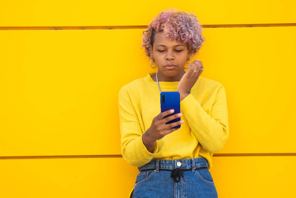 happy girl with mobile phone on yellow city wall - Zdjęcie, obraz