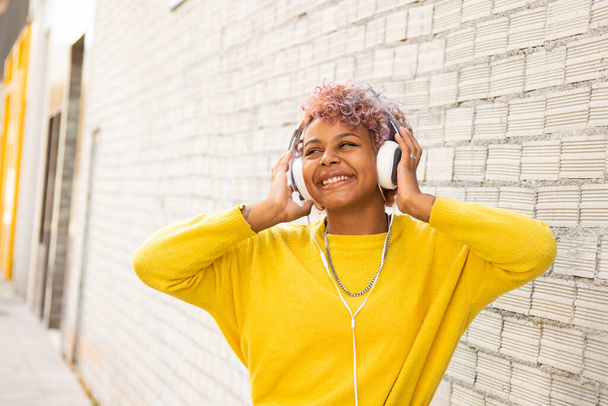 miejski styl afro amerykańska dziewczyna ze słuchawkami na zewnątrz uśmiechnięty - Zdjęcie, obraz