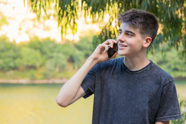 joven adolescente masculino con teléfono móvil al aire libre - Foto, imagen