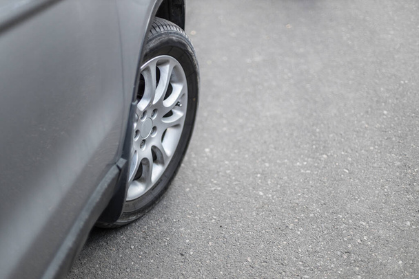 Front car wheel on the asphalt road with copyspace - Фото, изображение