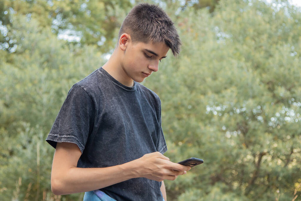 young male teenager with mobile phone outdoors - Foto, afbeelding