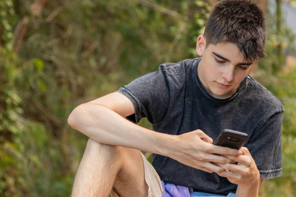 młody mężczyzna nastolatek z telefonu komórkowego na zewnątrz - Zdjęcie, obraz