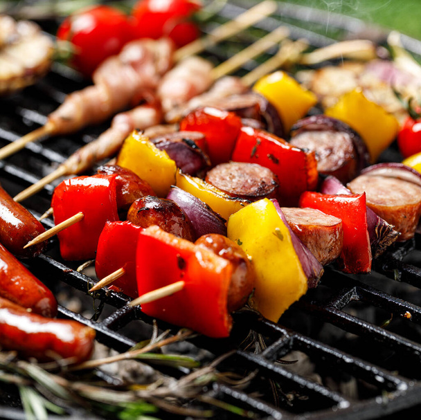 Grilled  meat and vegetable skewers on cast iron grill close up view - 写真・画像