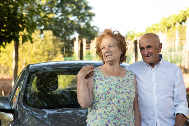 portret van senior paar met auto buiten - Foto, afbeelding