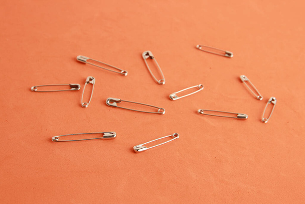 An close up shot of sewing pins on an orange colored background - Photo, image