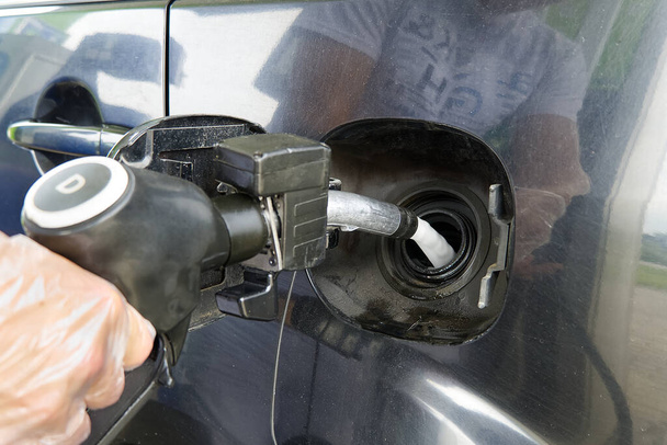 Egy férfi tankol egy fekete autót dízelüzemanyaggal egy benzinkútnál. Üzemanyag-feltöltő fúvóka közelről és sugárhajtómű. - Fotó, kép