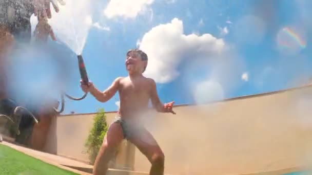 Zwei glückliche Kinder im Garten am Pool beim Wasserkampf. Spaß haben an einem sonnigen bewölkten Tag. - Filmmaterial, Video