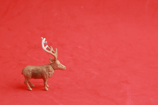 A closeup of a reindeer toy on a red surface under the lights - Fotoğraf, Görsel