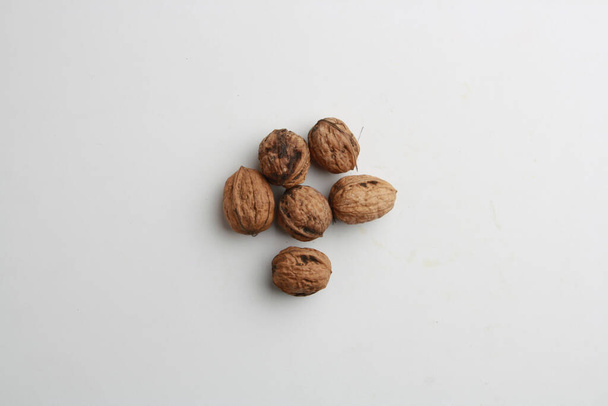 A top view of a pile of walnuts on a gray surface under the lights - Fotografie, Obrázek