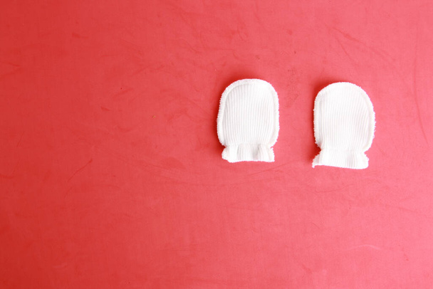 White wool mittens for a baby on a red surface - Foto, Bild