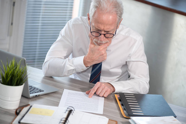 Старший бизнесмен проверяет документы в офисе - Фото, изображение