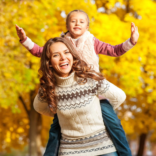 Mother and daughter having fun in the autumn park - Foto, afbeelding