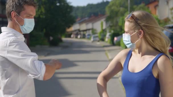 CLOSE UP: Junge Männer und Frauen mit medizinischen Masken grüßen durch Berührung der Ellbogen. - Filmmaterial, Video
