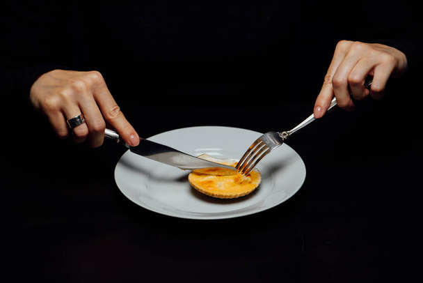 baked scallops in a shell with cheese on a white plate with a knife and fork on a black background - Foto, imagen