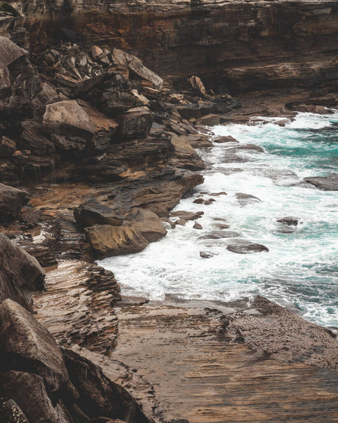 A beautiful vertical shot of a large cliff next to blue water on a gloomy day- perfect for wallpapers - Foto, immagini
